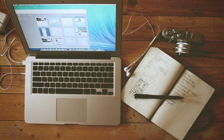 A laptop and a notebook on a wooden desk