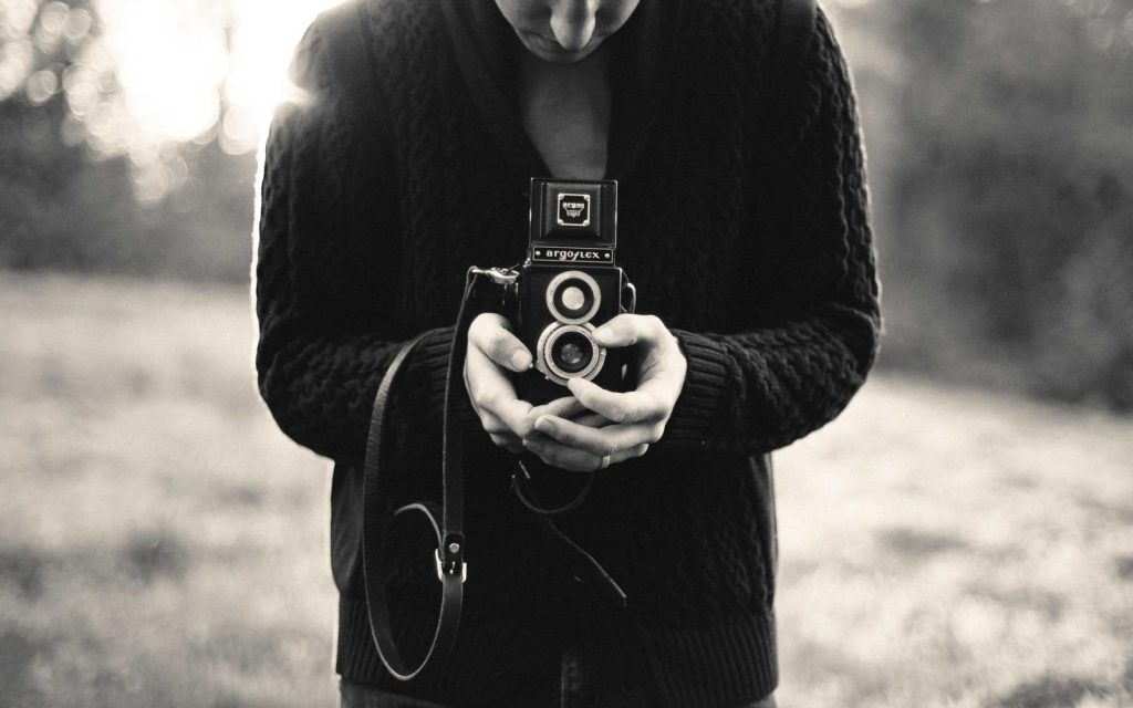 A photographer holding a twin-lens camera